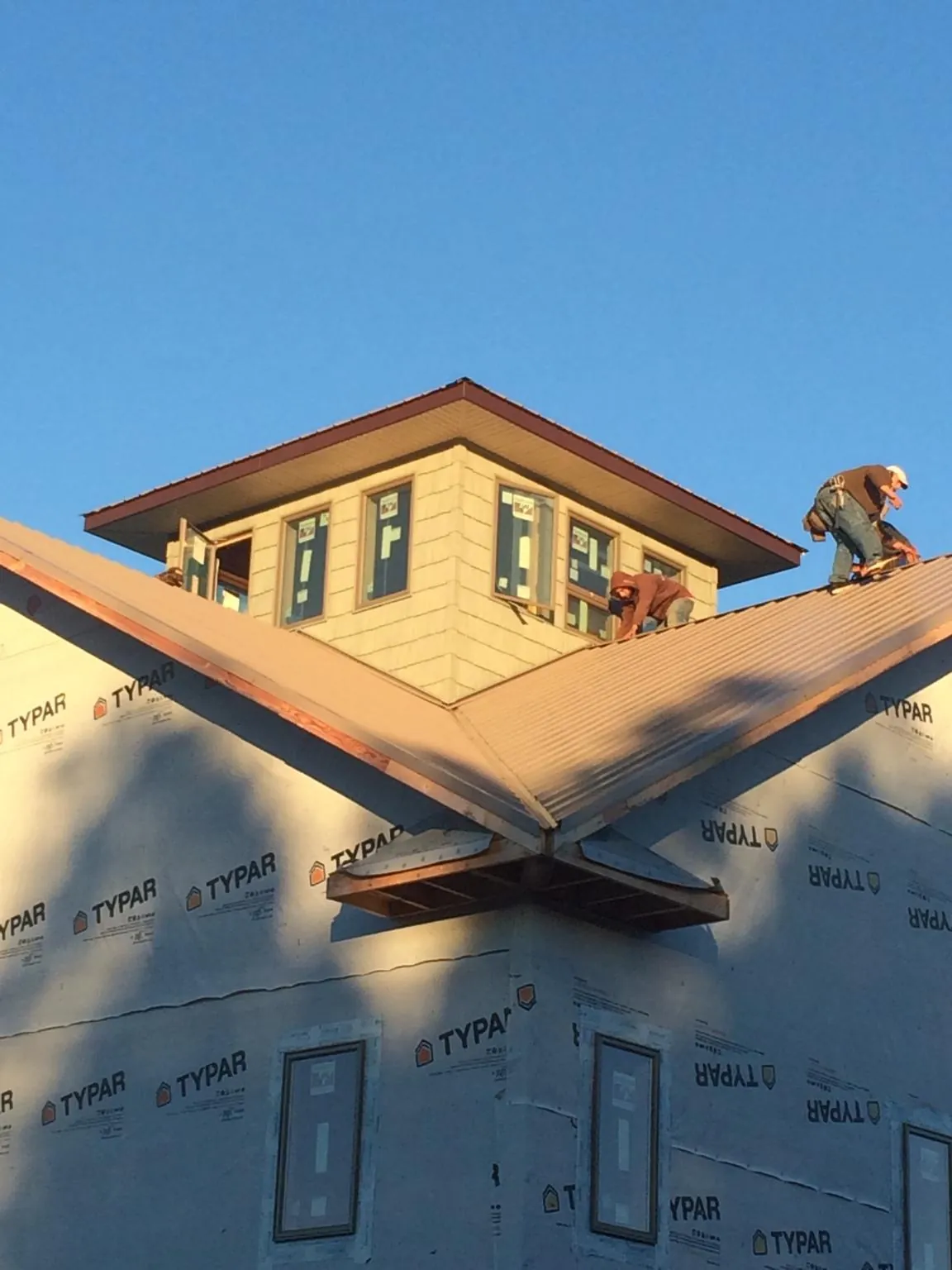 Roofers working around a rooftop cupola on a new metal roof at sunset — Roof Waterproofing in Harmony by Roofing Brothers
